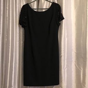 Black cocktail dress with black lace on shoulder.